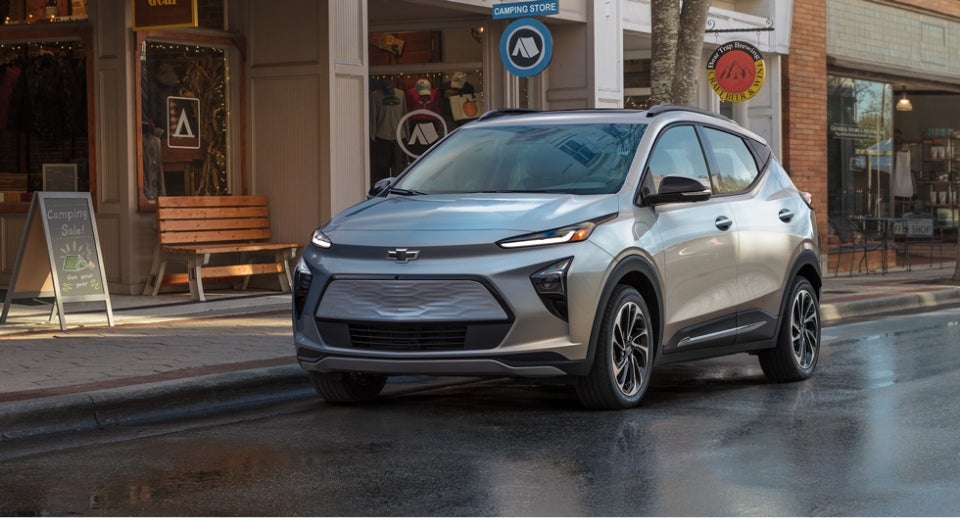 A Couple In Their Garage With the Man Plugging in the Charger for Their Chevrolet Bolt EV